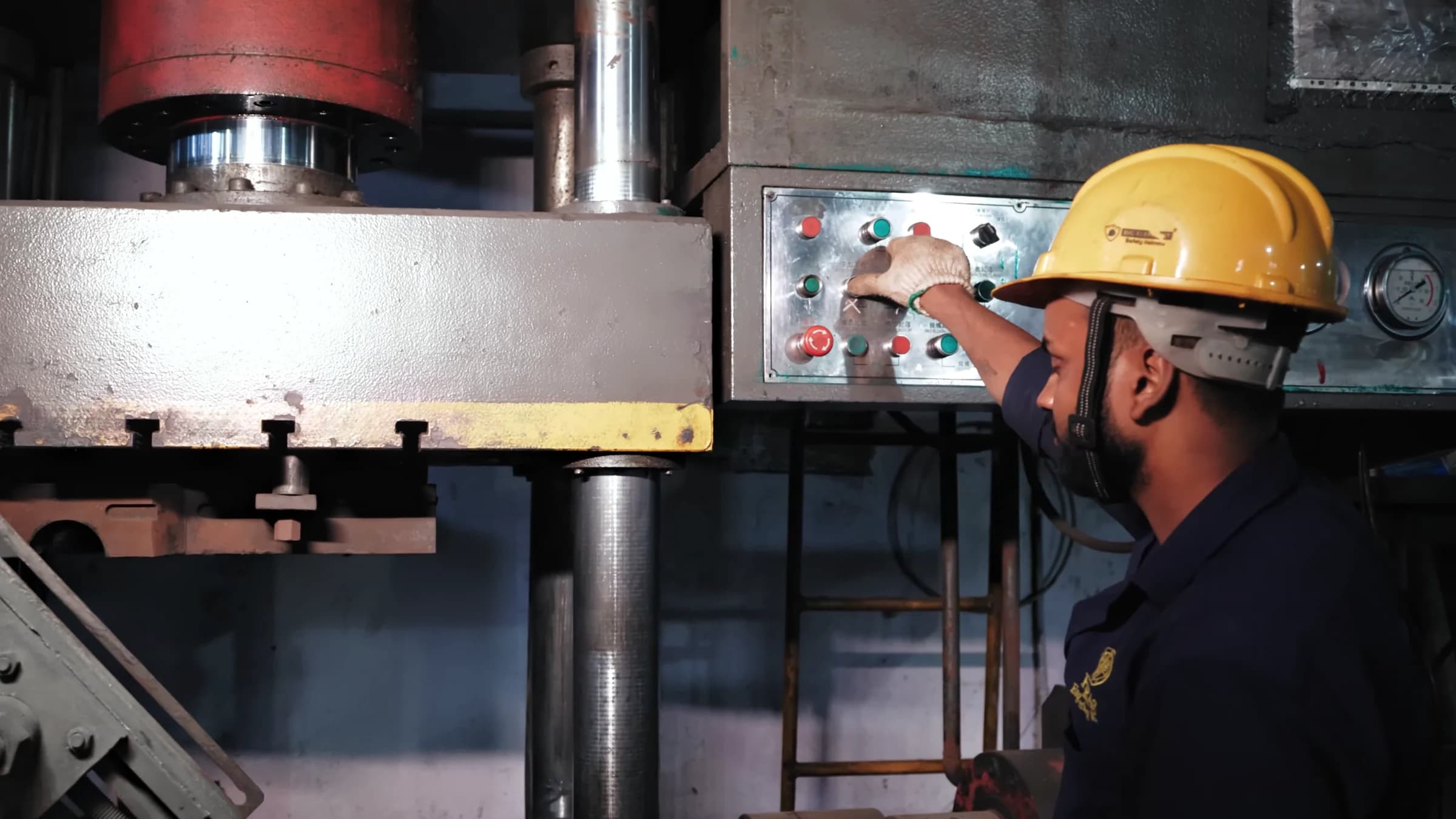 Operator in a safety helmet and gloves at the controls of the cold bending machine