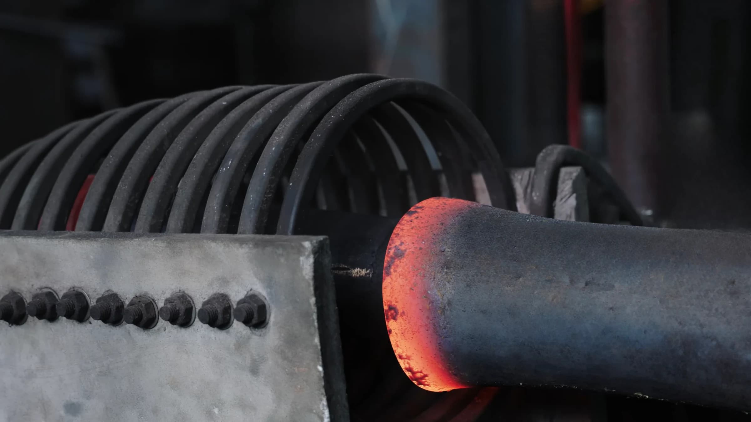 Pipe glowing red-hot as it leaves the induction coil of the mandrel elbow machine