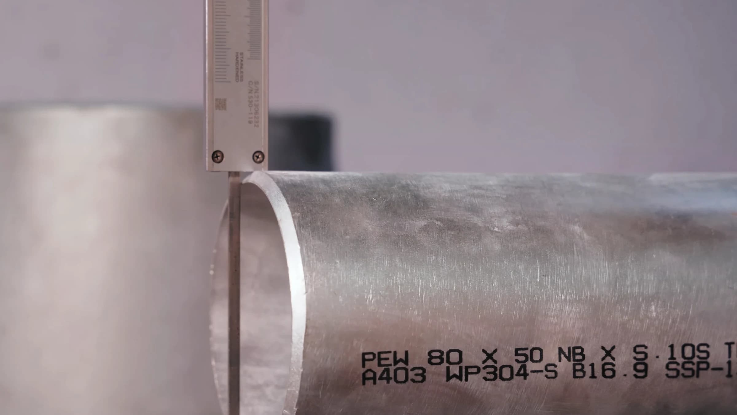 Vernier caliper on the end of a stainless-steel tee marked A403 WP304-S B16.9
