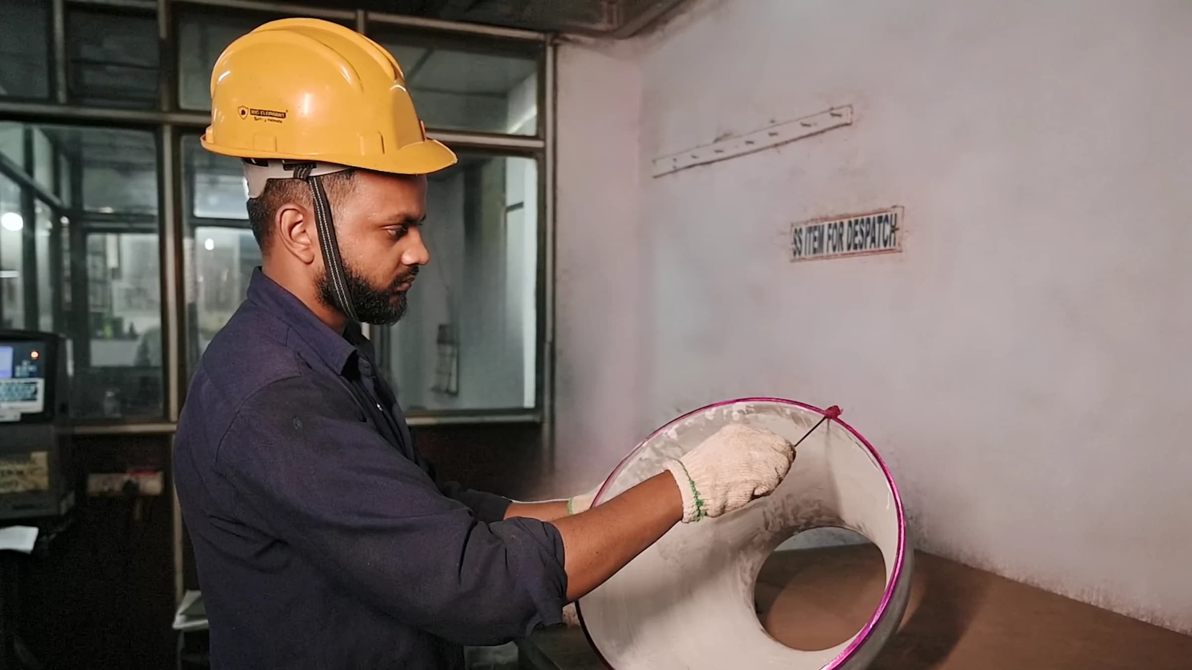Inspector in a safety helmet and gloves running a dye-penetrant test on a stainless-steel fitting
