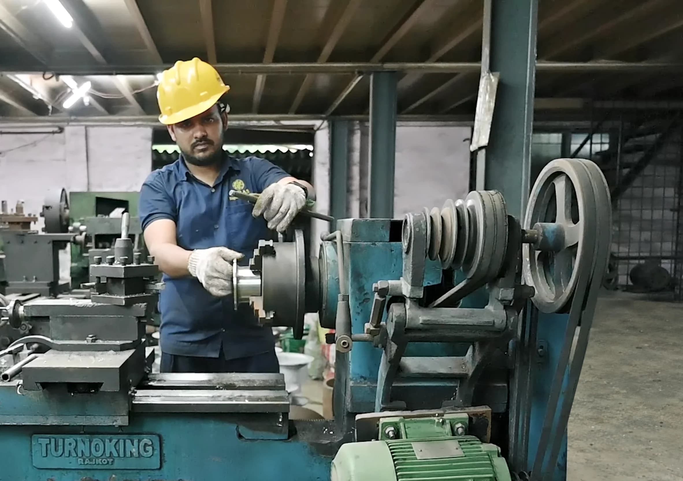 Operator in a safety helmet and gloves turning a fitting on a lathe
