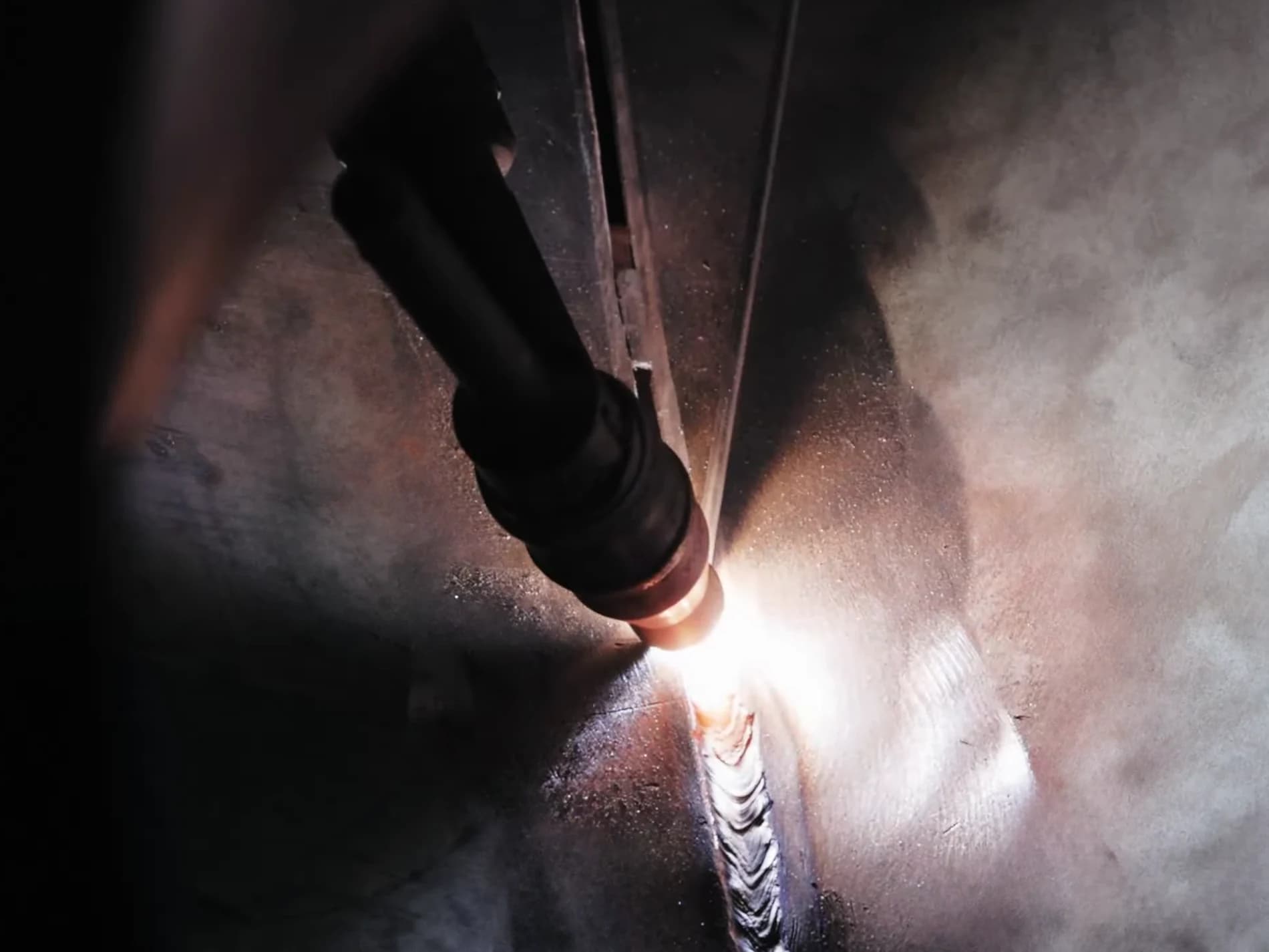 TIG torch and a fresh weld bead on a fitting seam